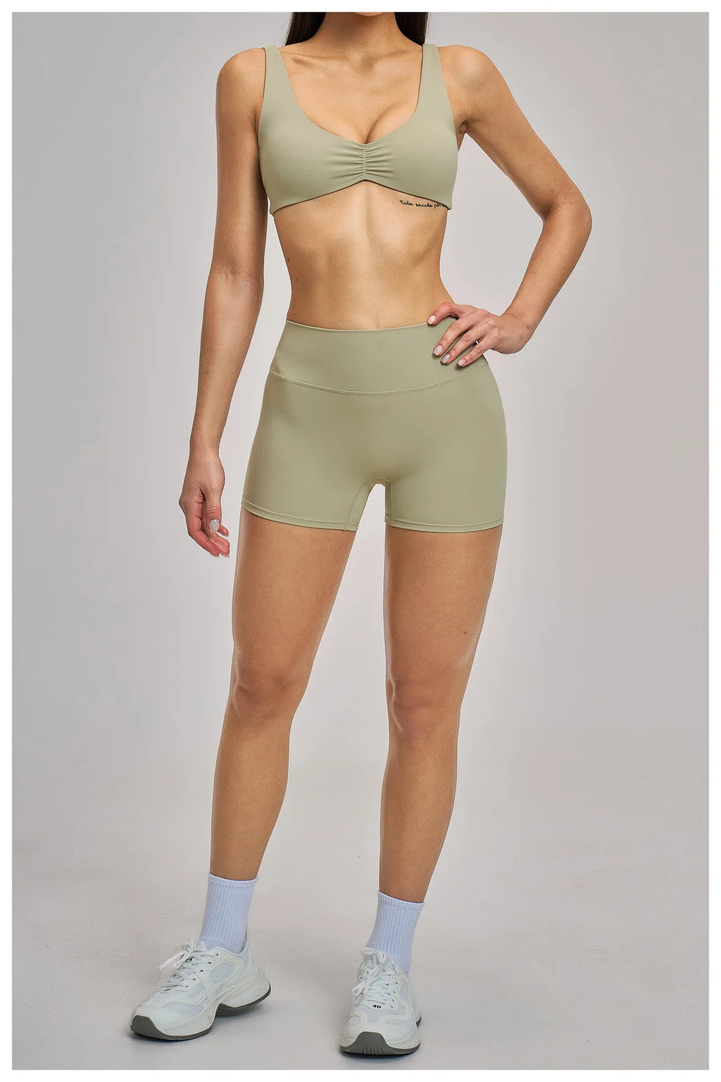 Person wearing a green sports bra and shorts set on a gray background