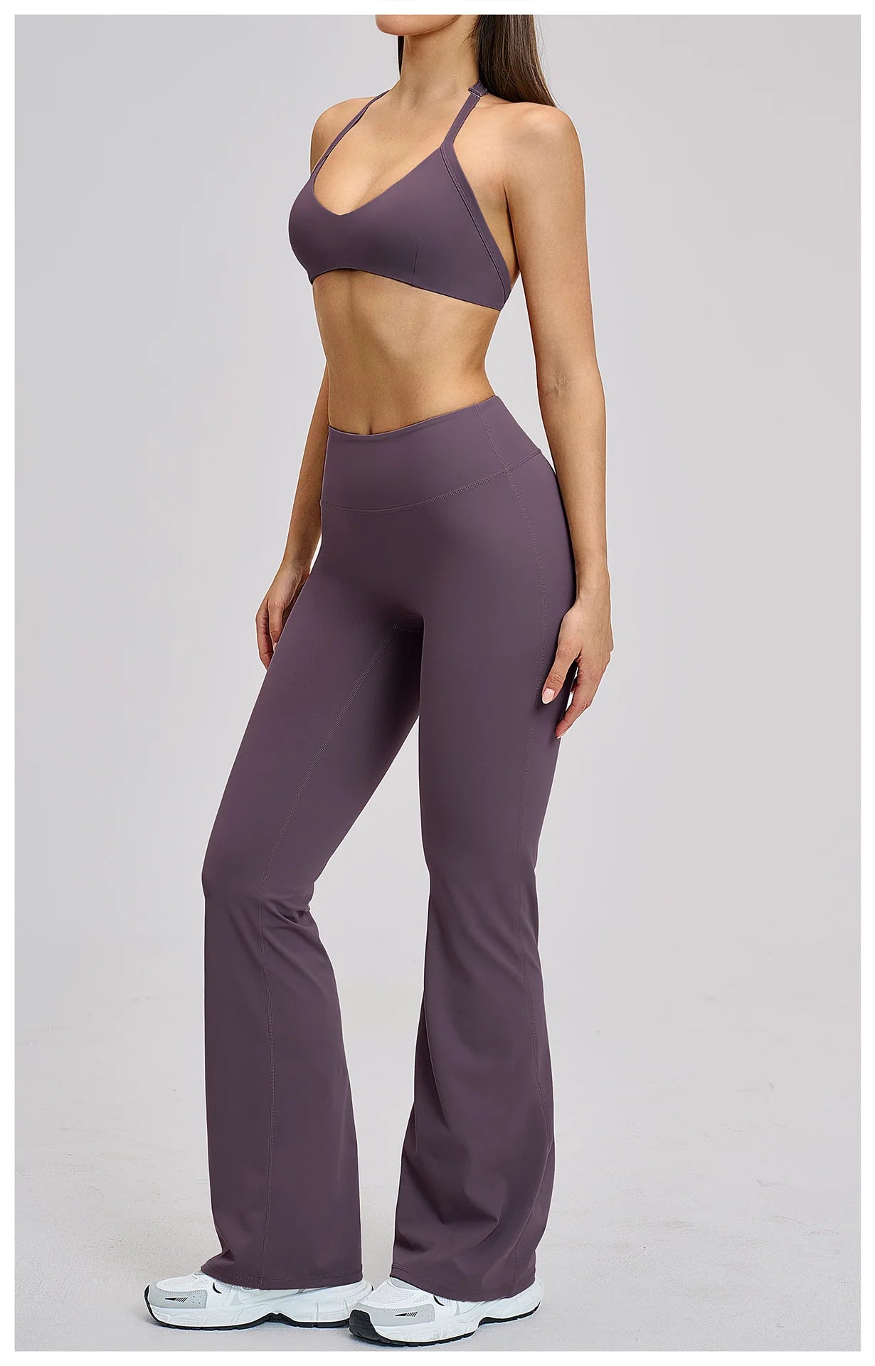 Person wearing a purple sports bra and leggings set on a light gray background