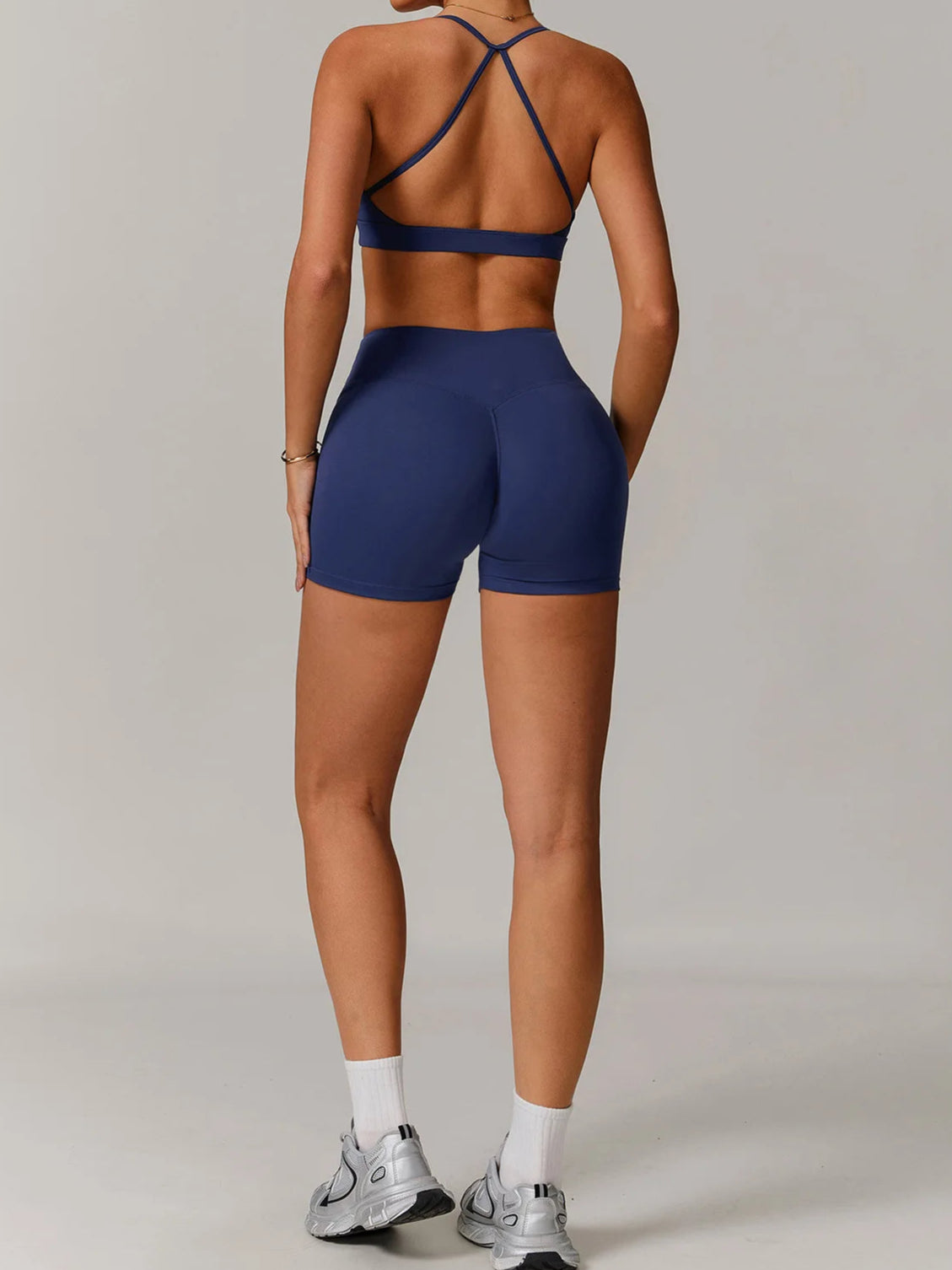 Person wearing a navy blue sports bra and shorts set on a plain background