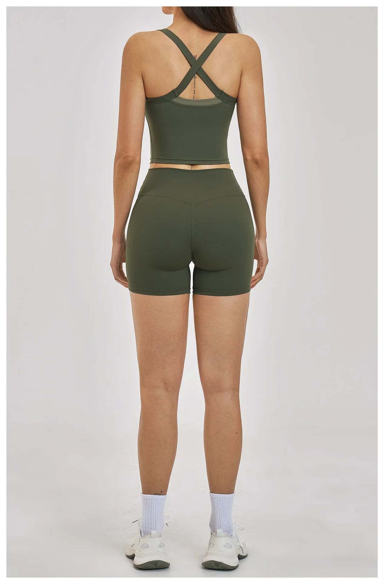 Person wearing a green sports bra and shorts set on a white background