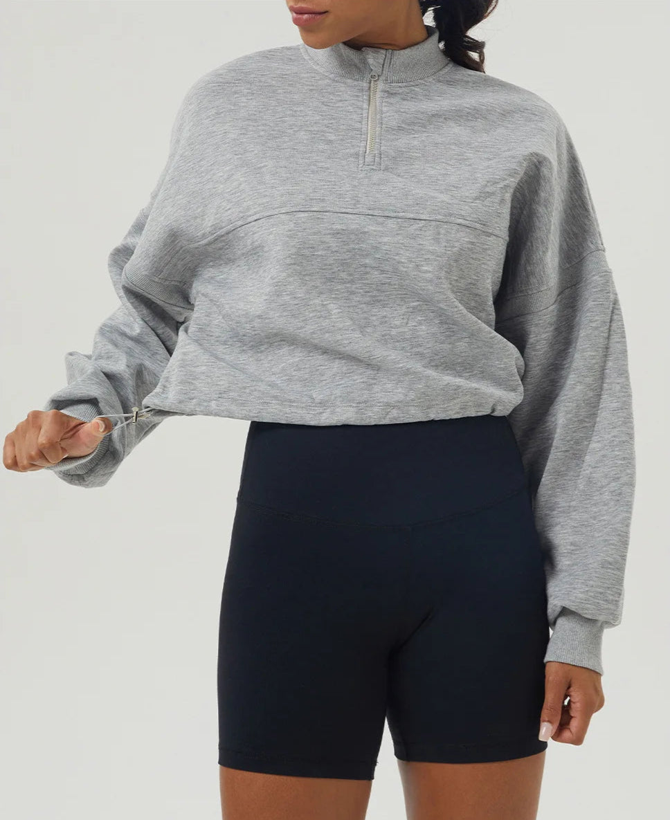 Person wearing a gray sweatshirt and black shorts on a white background