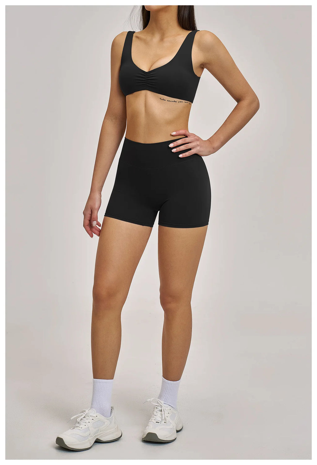 Person wearing a black sports bra and shorts on a plain background