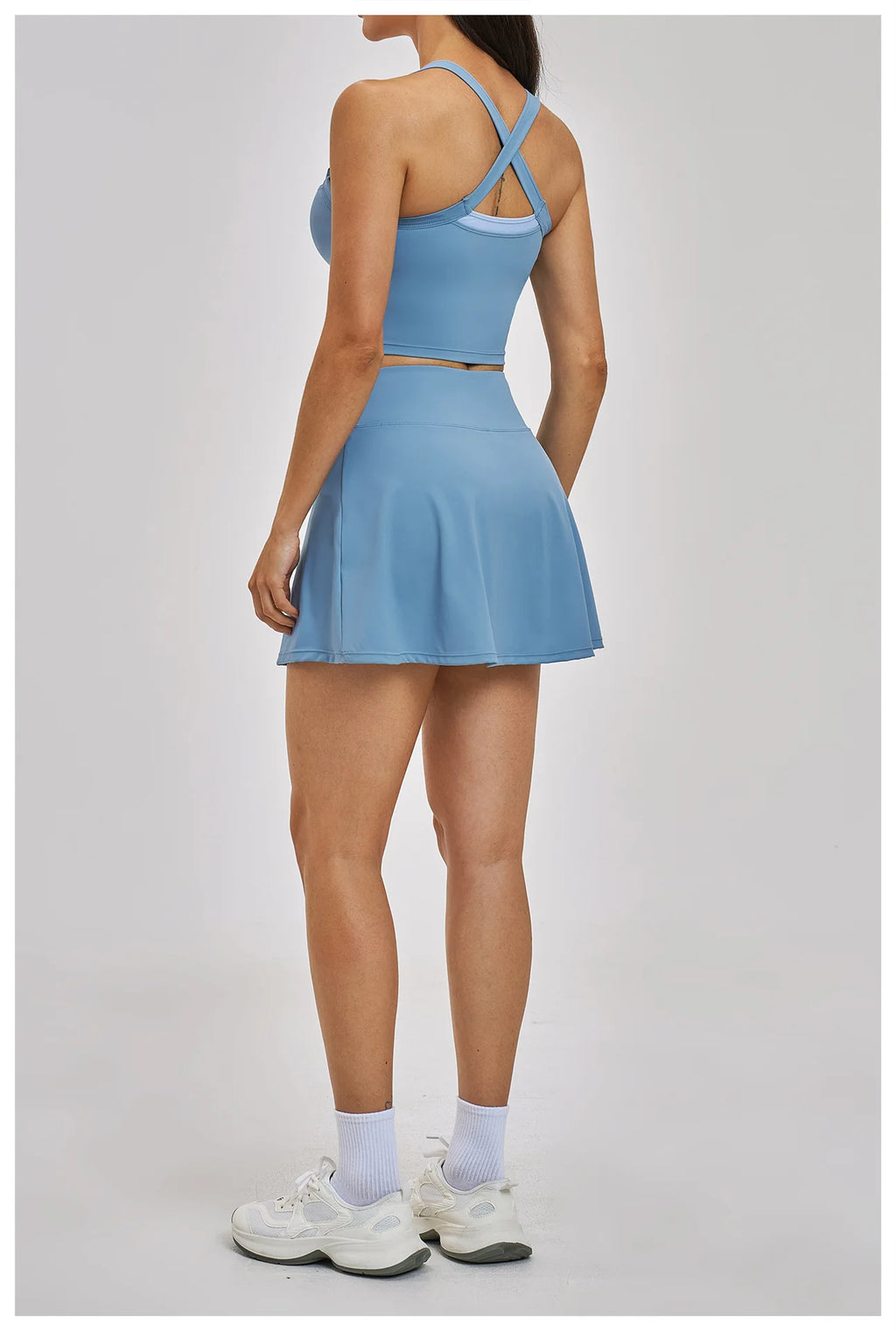 Person wearing a blue tennis dress on a light gray background