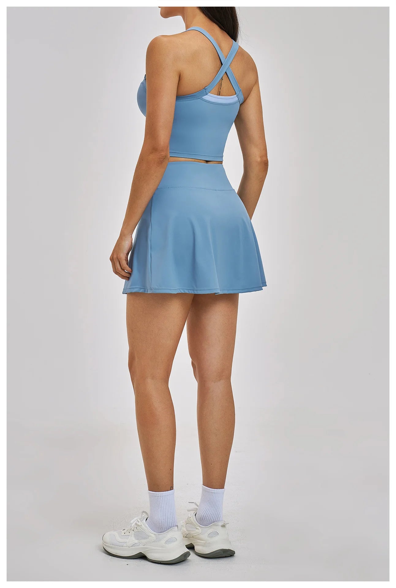 Person wearing a blue tennis dress on a light gray background