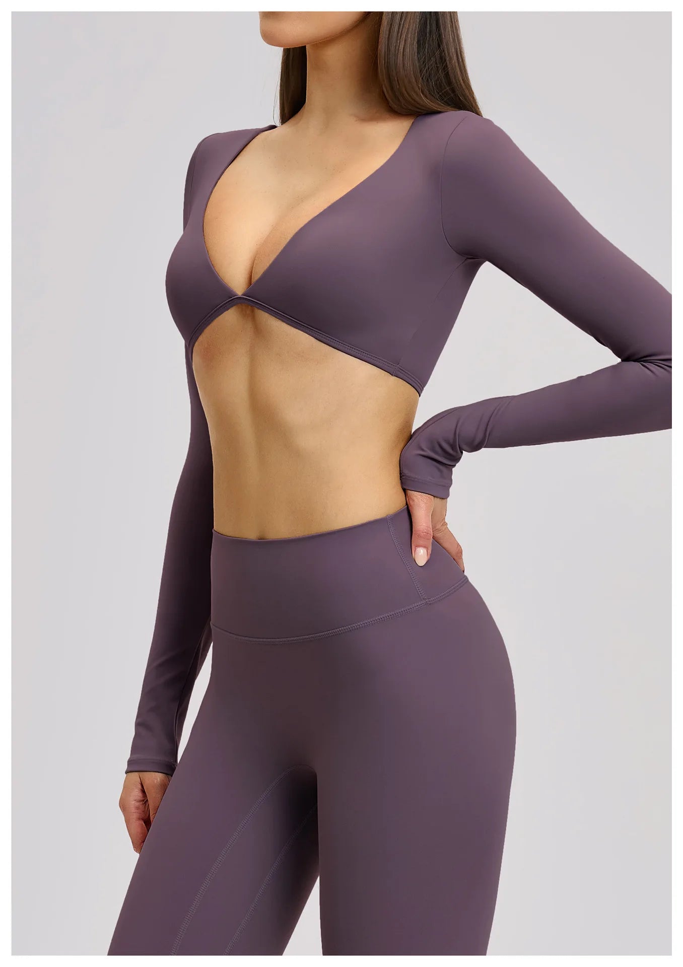 Person wearing a purple long-sleeve top and leggings on a light gray background
