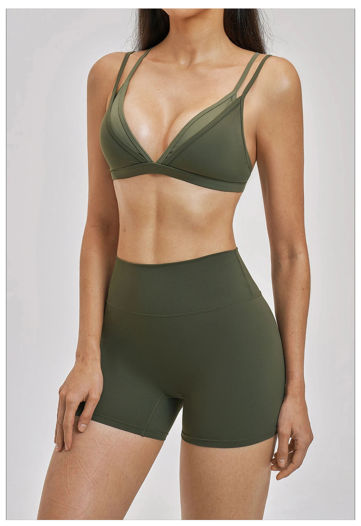 Person wearing a green sports bra and shorts set on a plain background