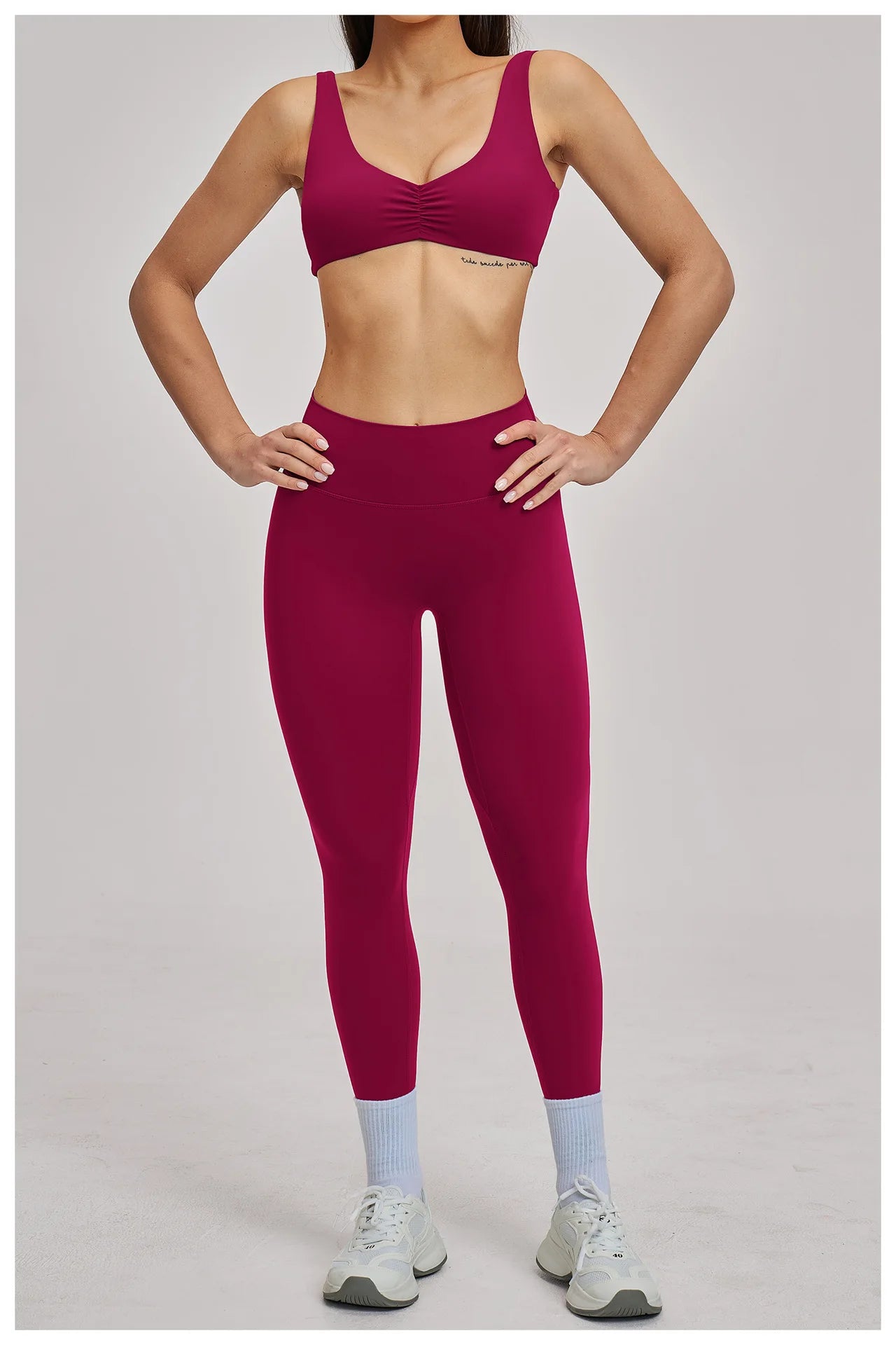 Person wearing a cherry red sports bra and leggings on a plain background