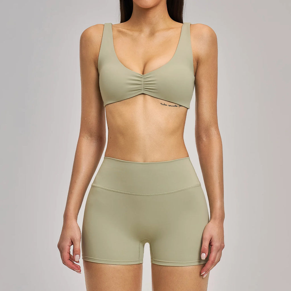 Person wearing a green sports bra and shorts set on a gray background