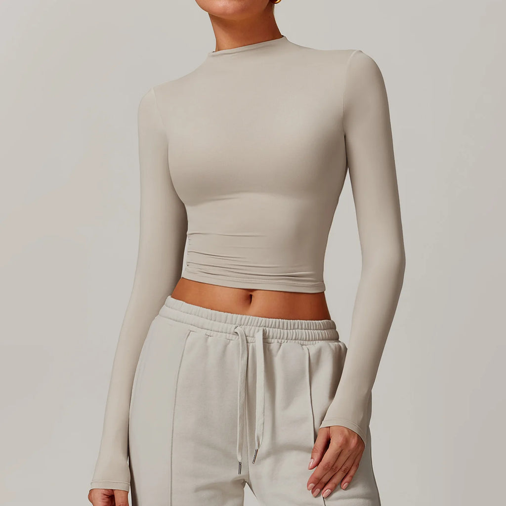 Person wearing a beige long-sleeve crop top and matching pants against a plain background