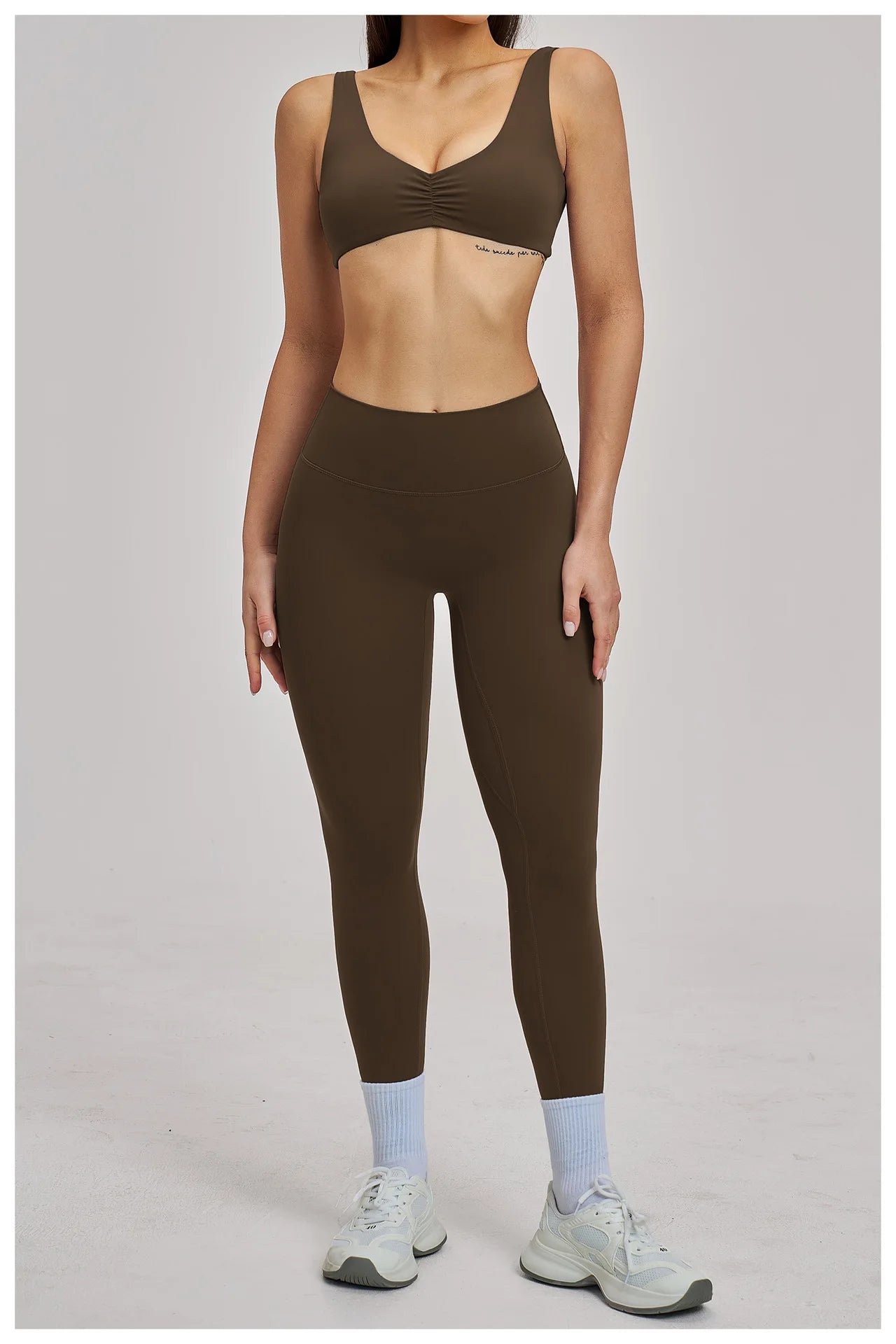 Person wearing a brown sports bra and leggings set on a plain background