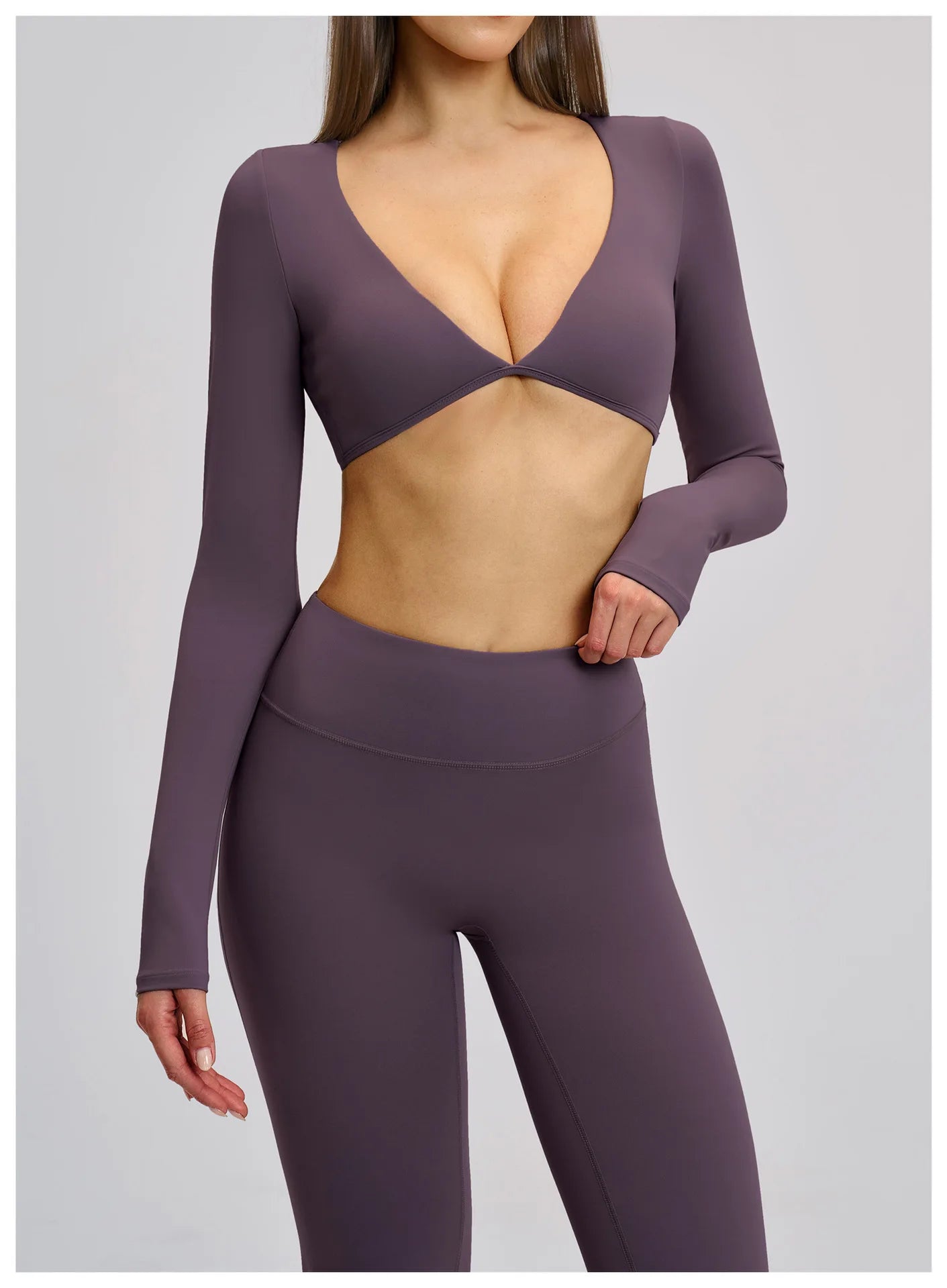 Person wearing a purple long-sleeve top and leggings on a gray background