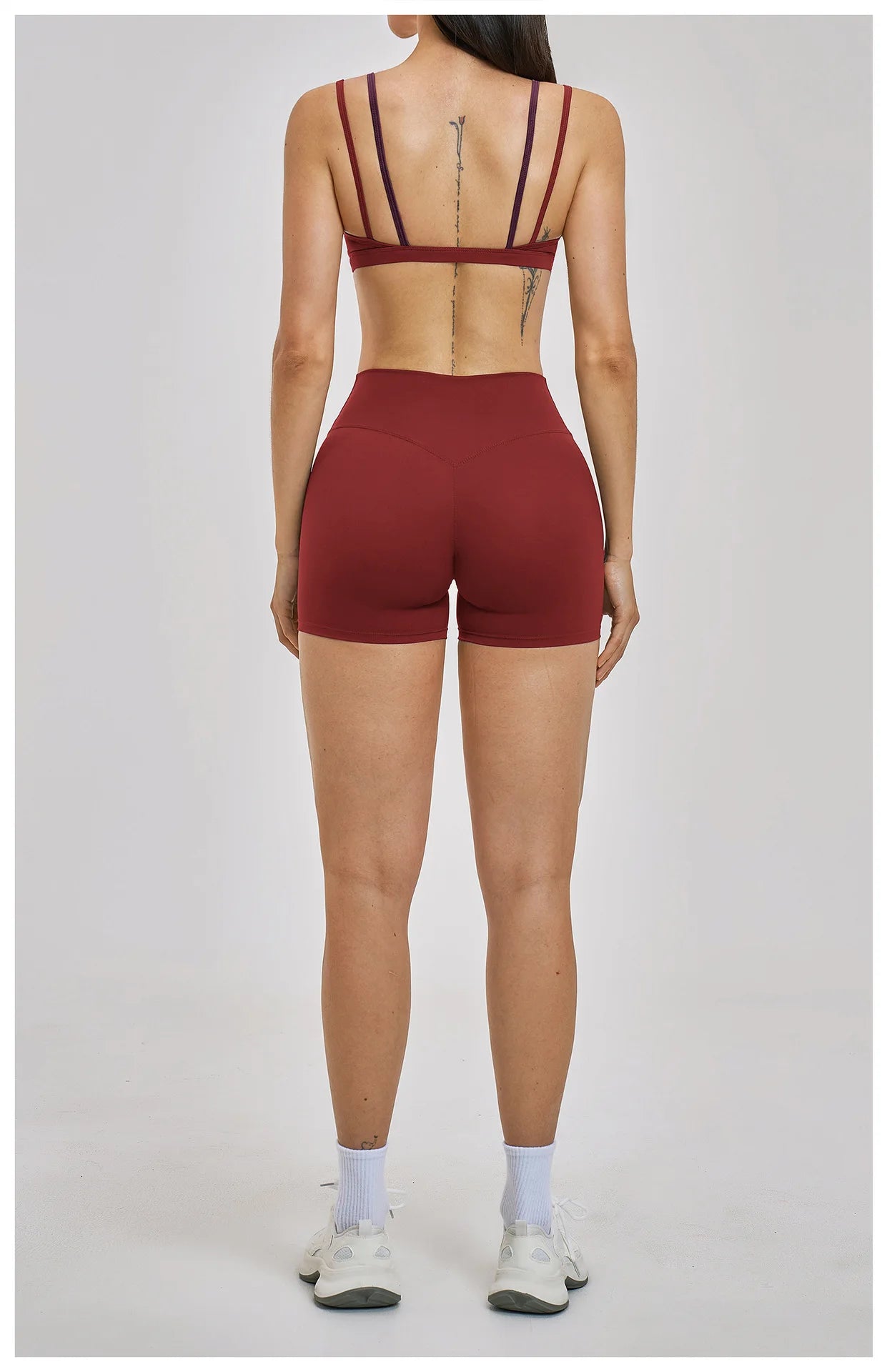 Person wearing a red sports bra and shorts on a white background