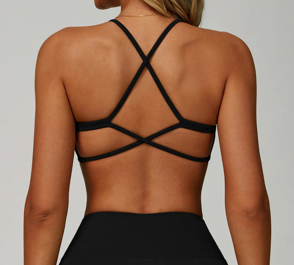 Black strappy top worn by a person on a plain background