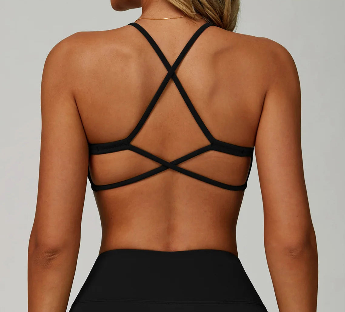 Black strappy top worn by a person on a plain background