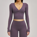 Purple long-sleeve athletic top and leggings set on a gray background