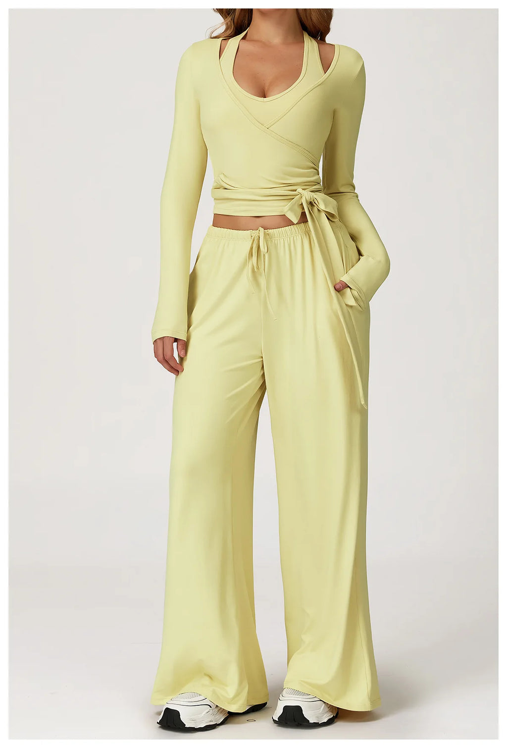 Person wearing a light yellow long-sleeve ballet wrap top and wide-leg pants on a white background