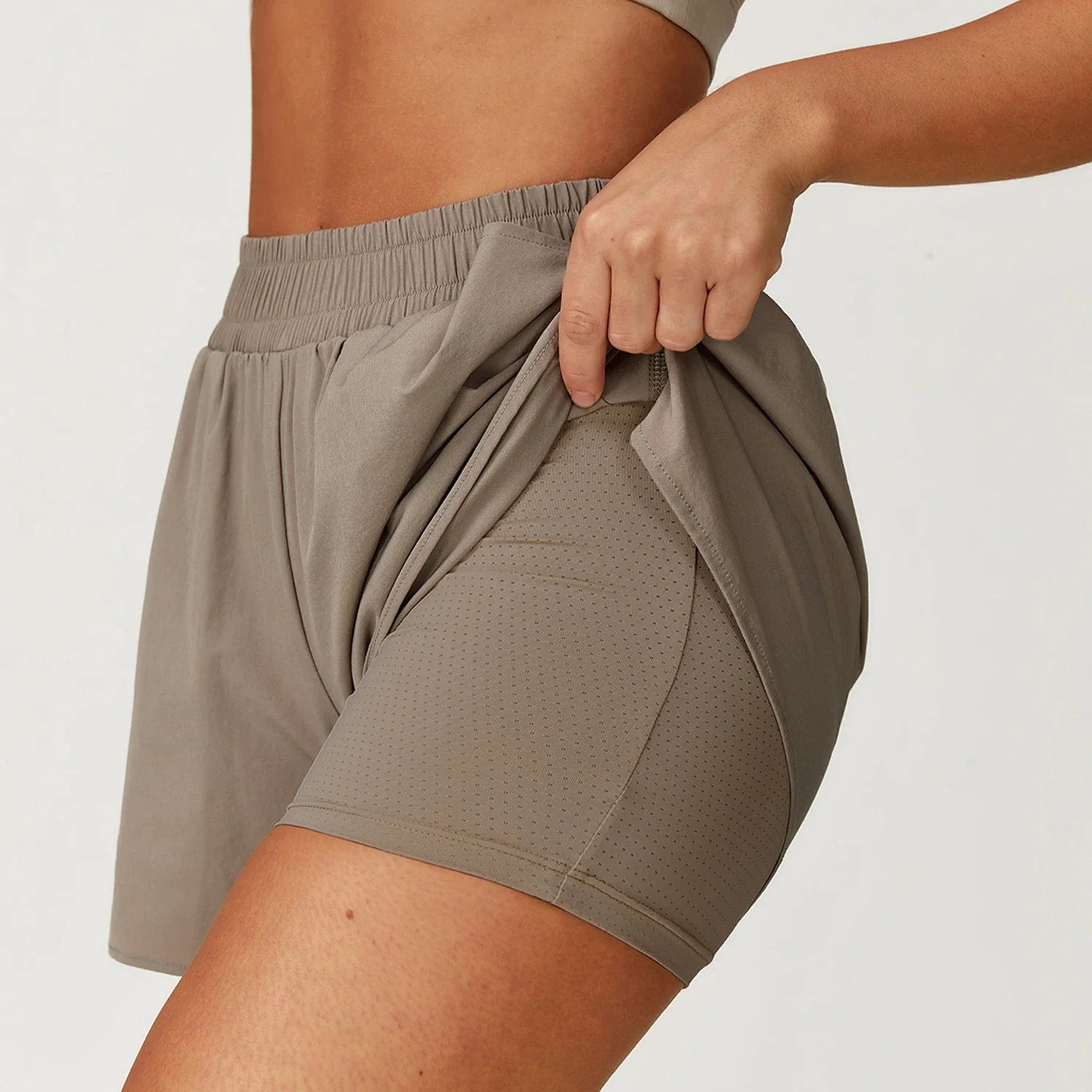 Person wearing a pair of brown athletic shorts on a plain background