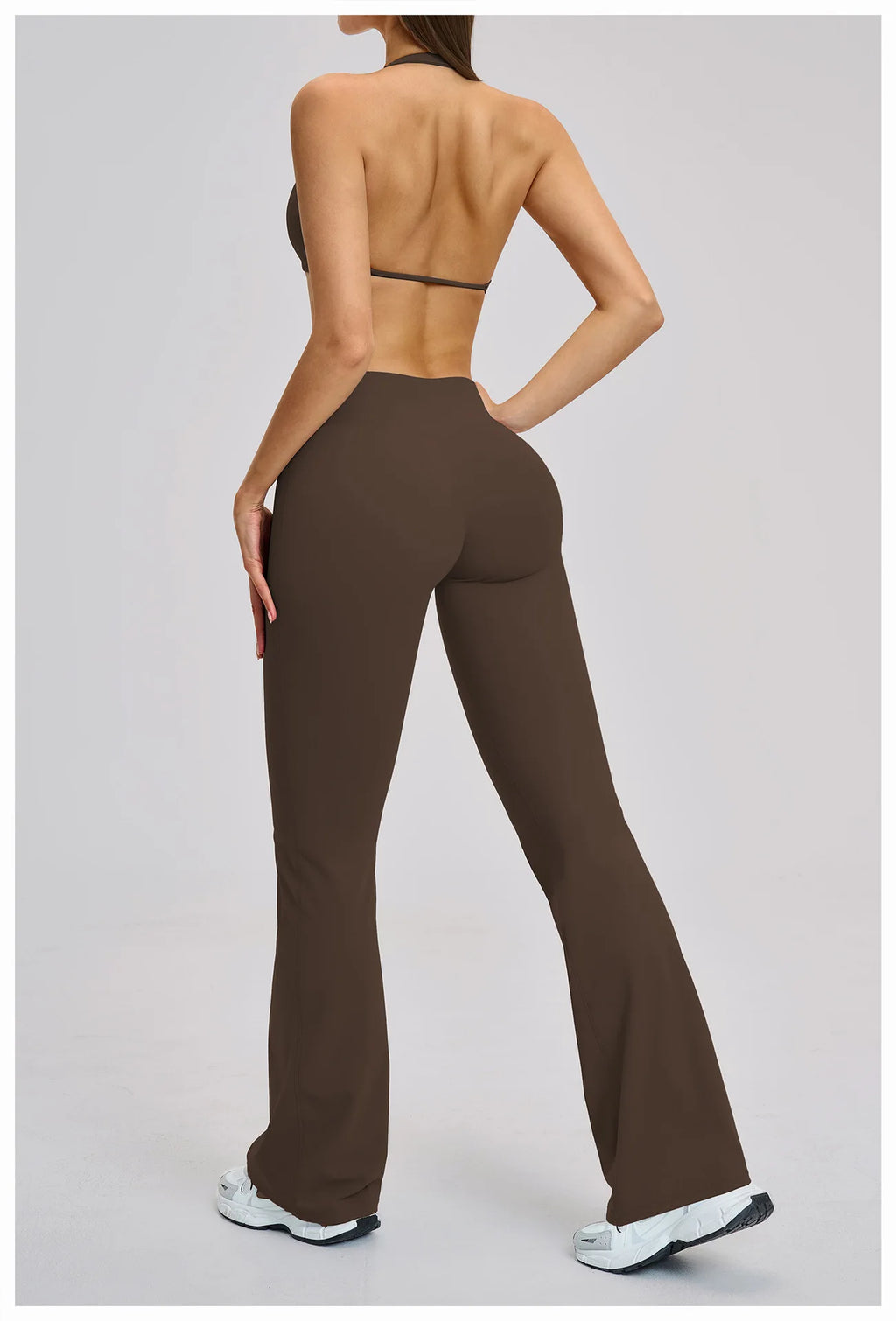 Person wearing brown high-waisted pants on a plain background