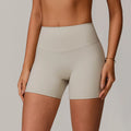Beige high-waisted shorts worn by a person on a neutral background