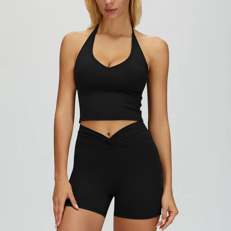 Woman wearing a black sports bra and high-waisted shorts on a light gray background