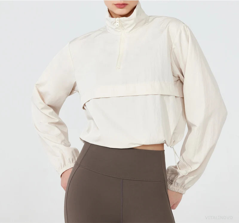 Person wearing a beige long-sleeve top and brown pants on a white background