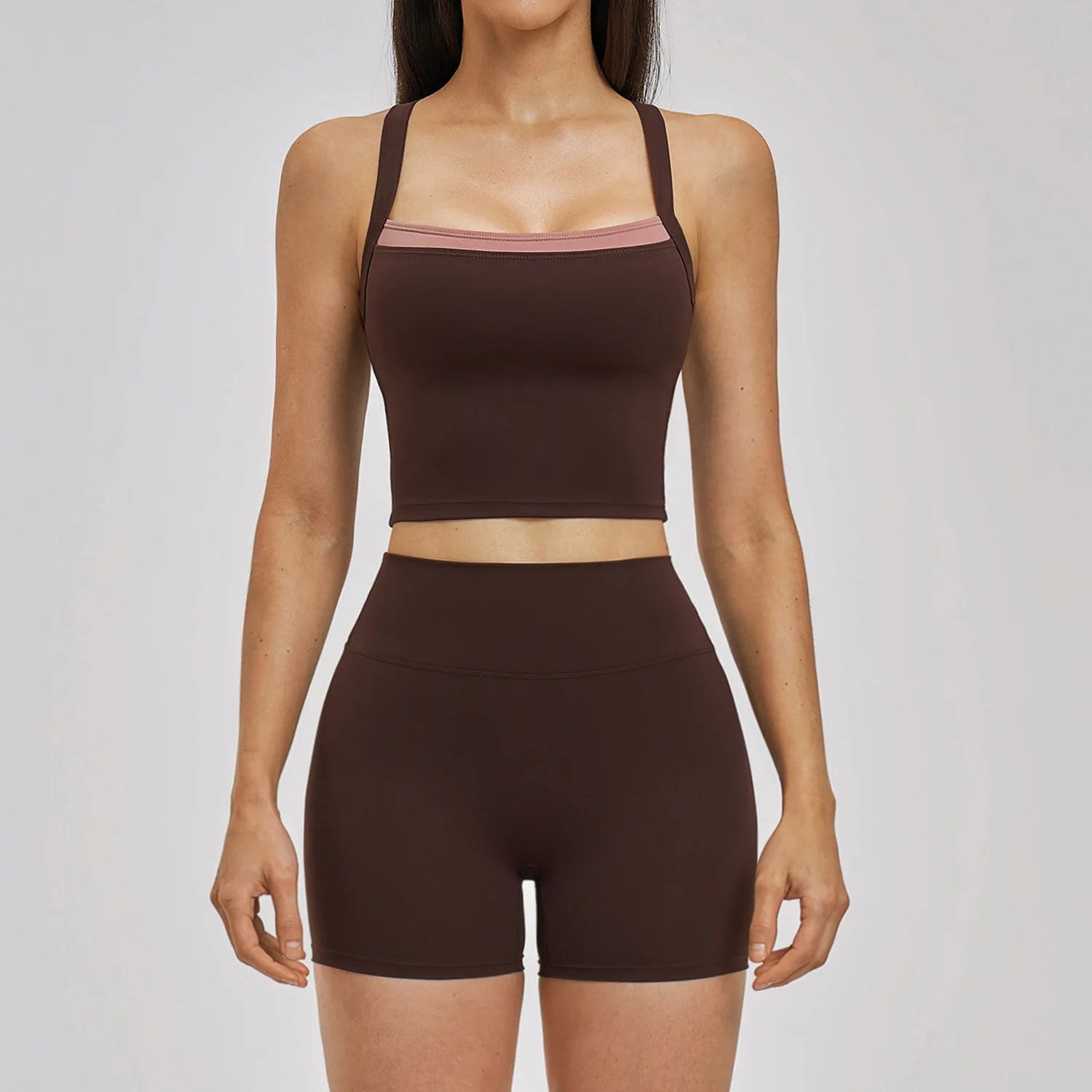 Woman wearing a brown sports bra and shorts set on a light gray background
