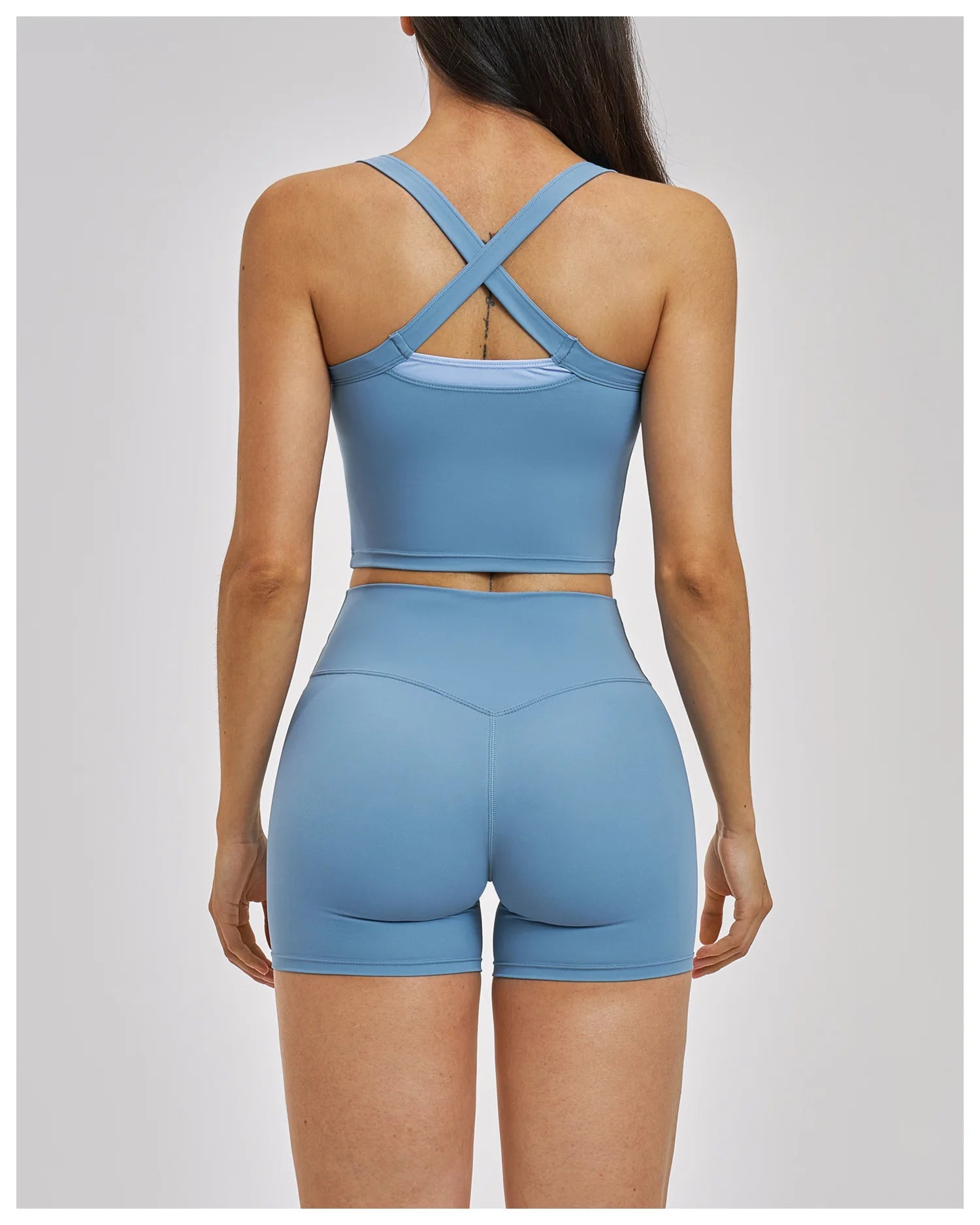 Woman wearing a blue sports bra and shorts set on a gray background