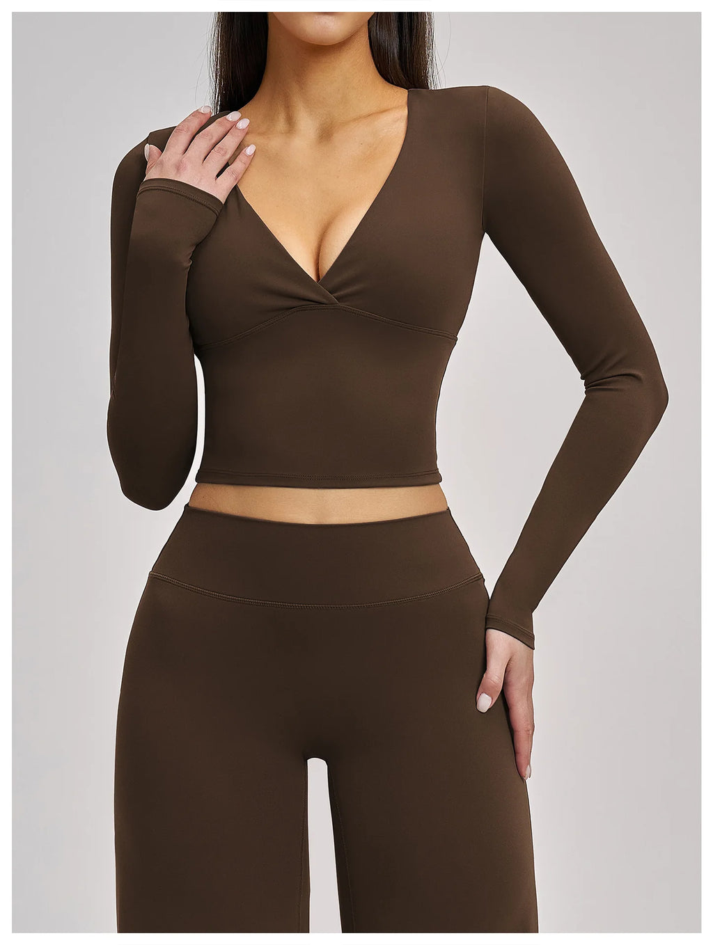 Woman wearing a brown long-sleeve top and high-waisted leggings on a light gray background