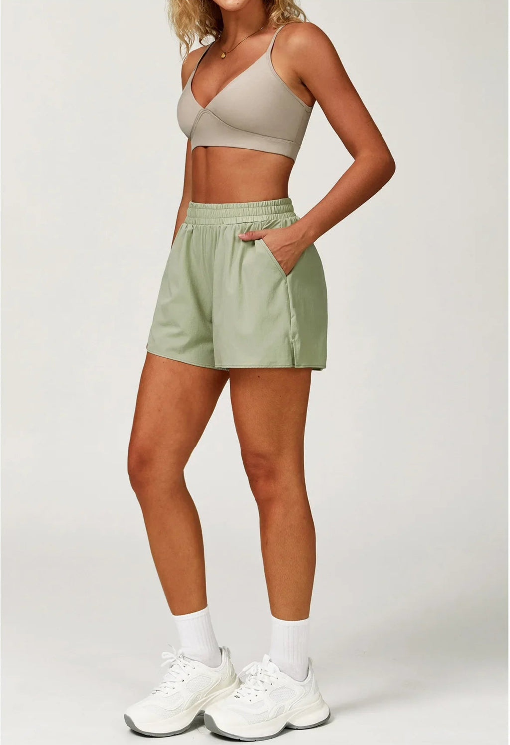 Person wearing a beige crop top and light green shorts on a white background