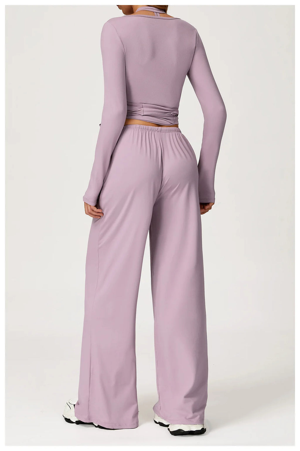 Person wearing a purple long-sleeve top and wide-leg pants set on a white background