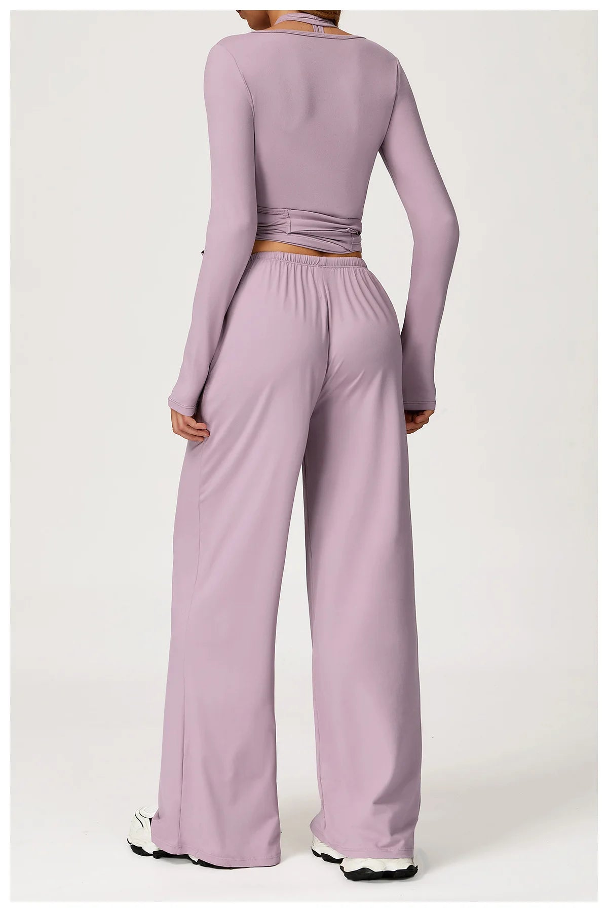 Person wearing a purple long-sleeve top and wide-leg pants set on a white background