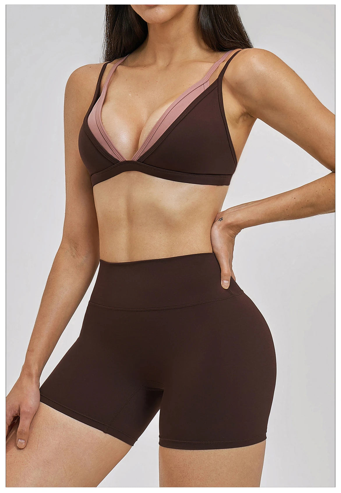Woman wearing a brown sports bra and shorts set on a plain background