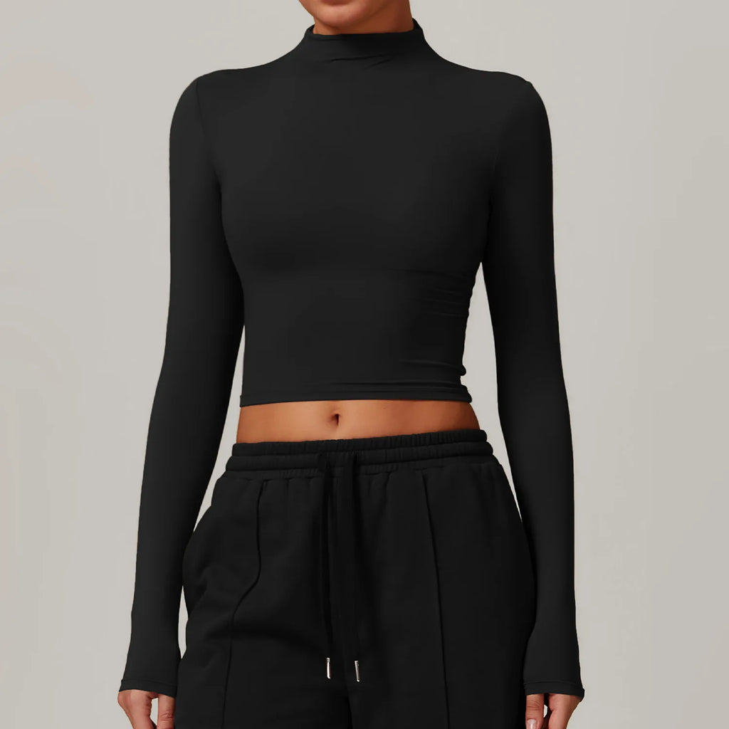 Person wearing a black long-sleeve crop top and black pants on a gray background