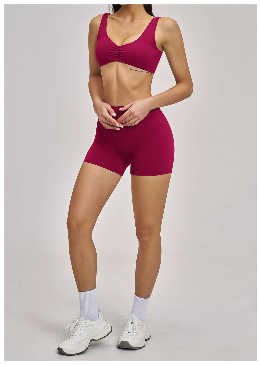 Person wearing a maroon sports bra and shorts set on a plain background