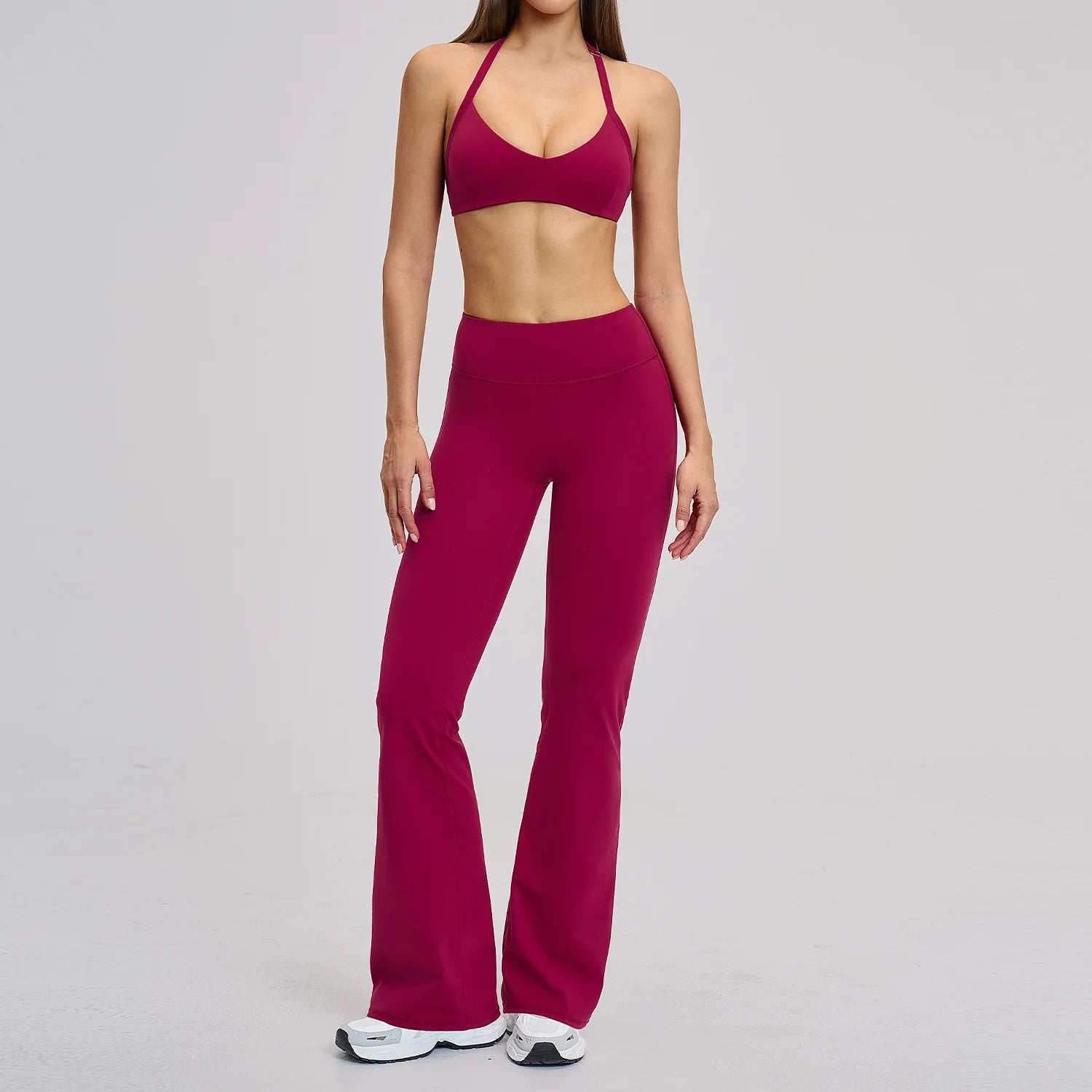 Person wearing a magenta sports bra and leggings set on a gray background