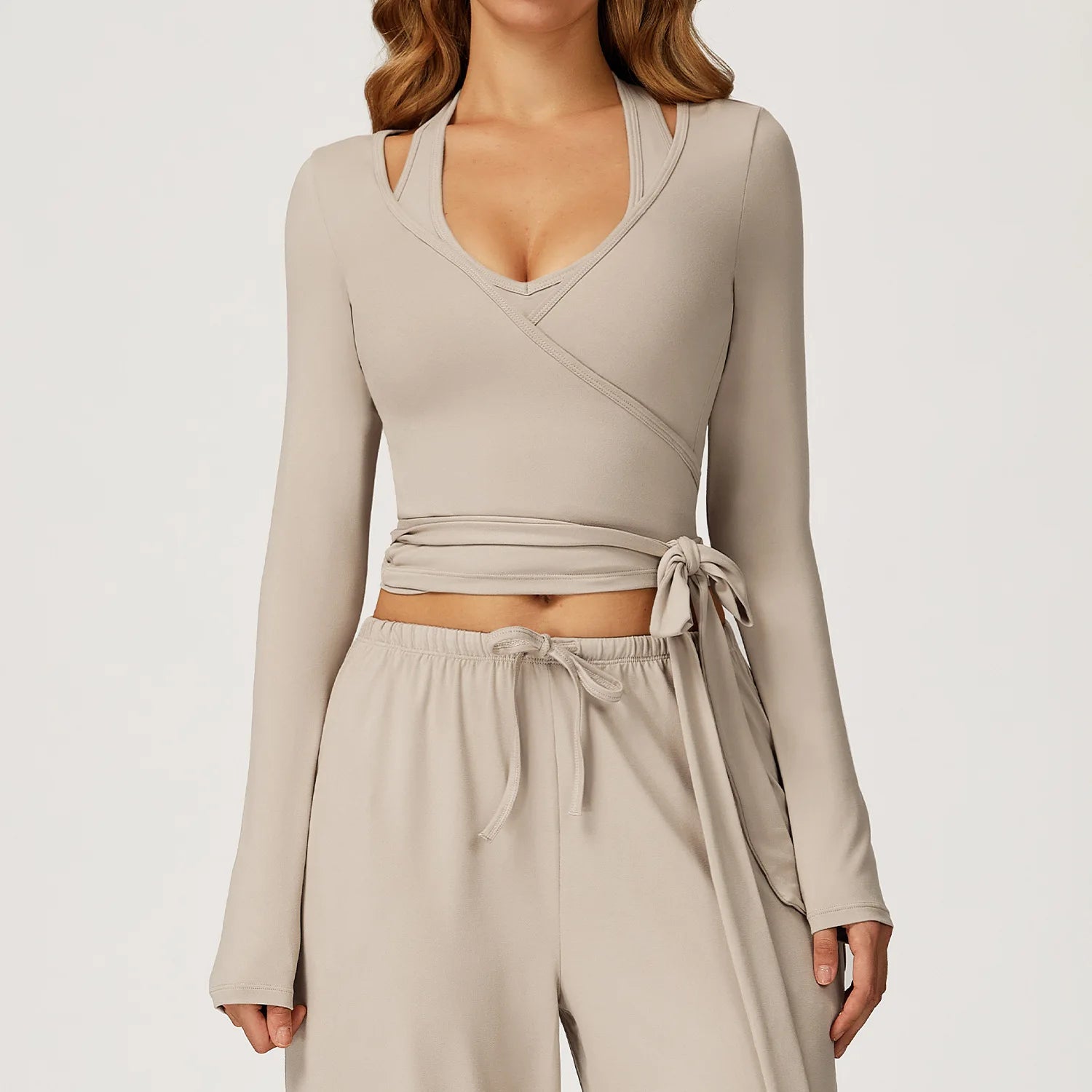 Beige long-sleeve ballet wrap top and pants set on a plain background