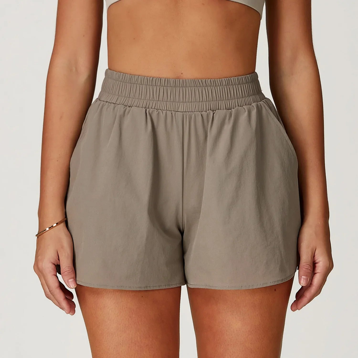 Person wearing beige running shorts on a plain background