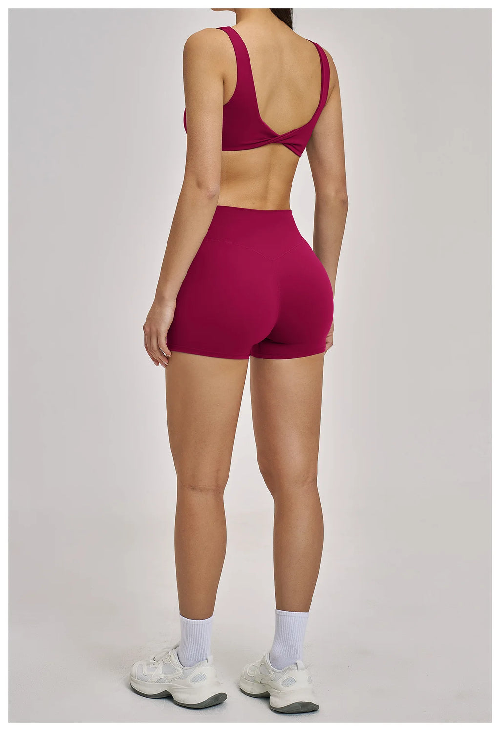 Person wearing a red sports bra and shorts on a plain background