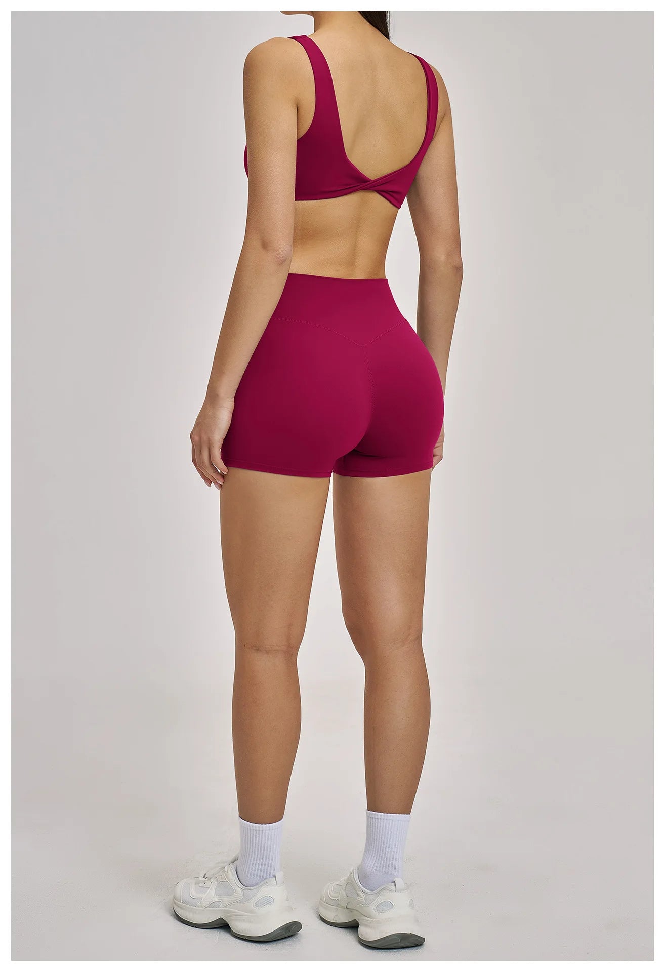 Person wearing a red sports bra and shorts on a plain background