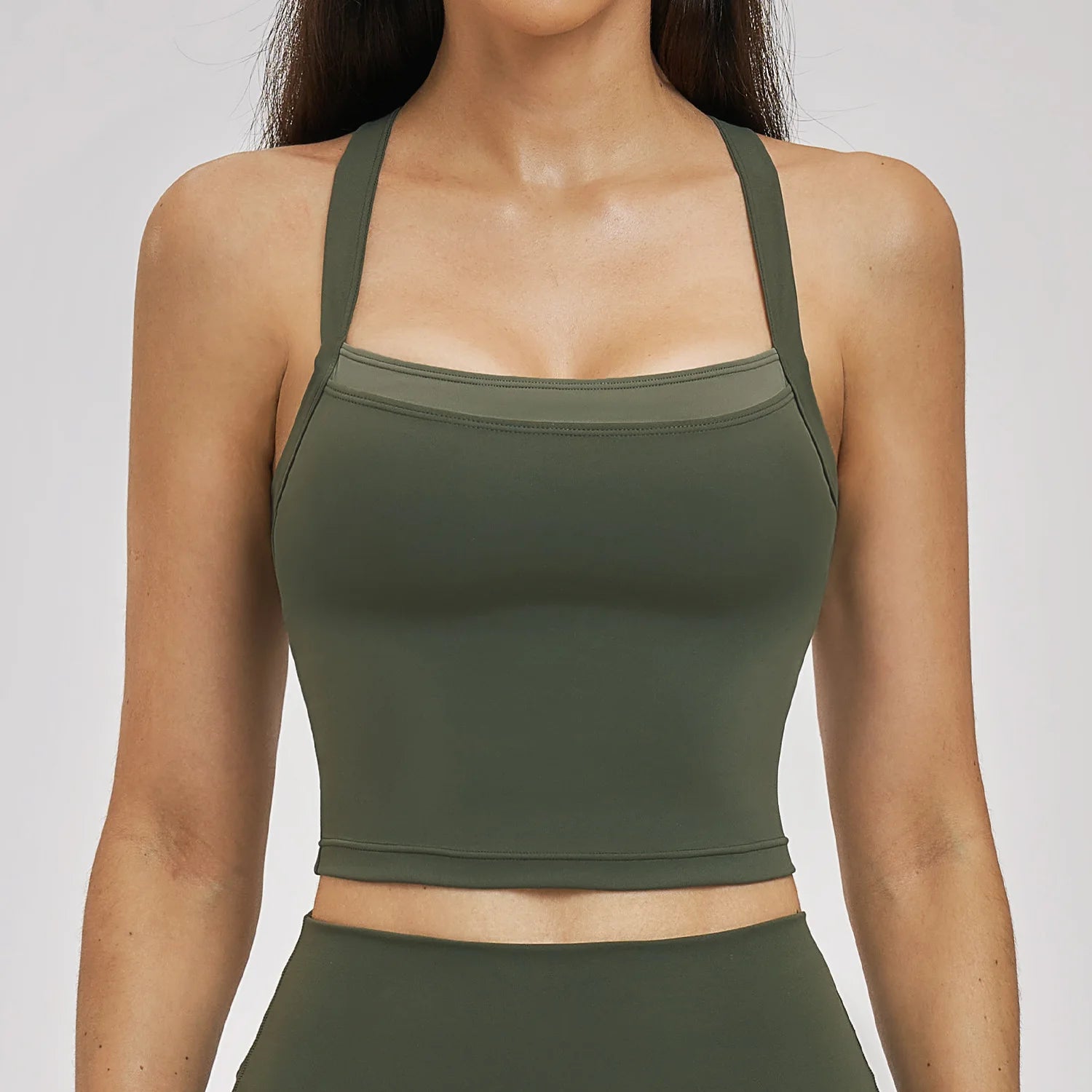 Person wearing a green sports bra and leggings on a plain background