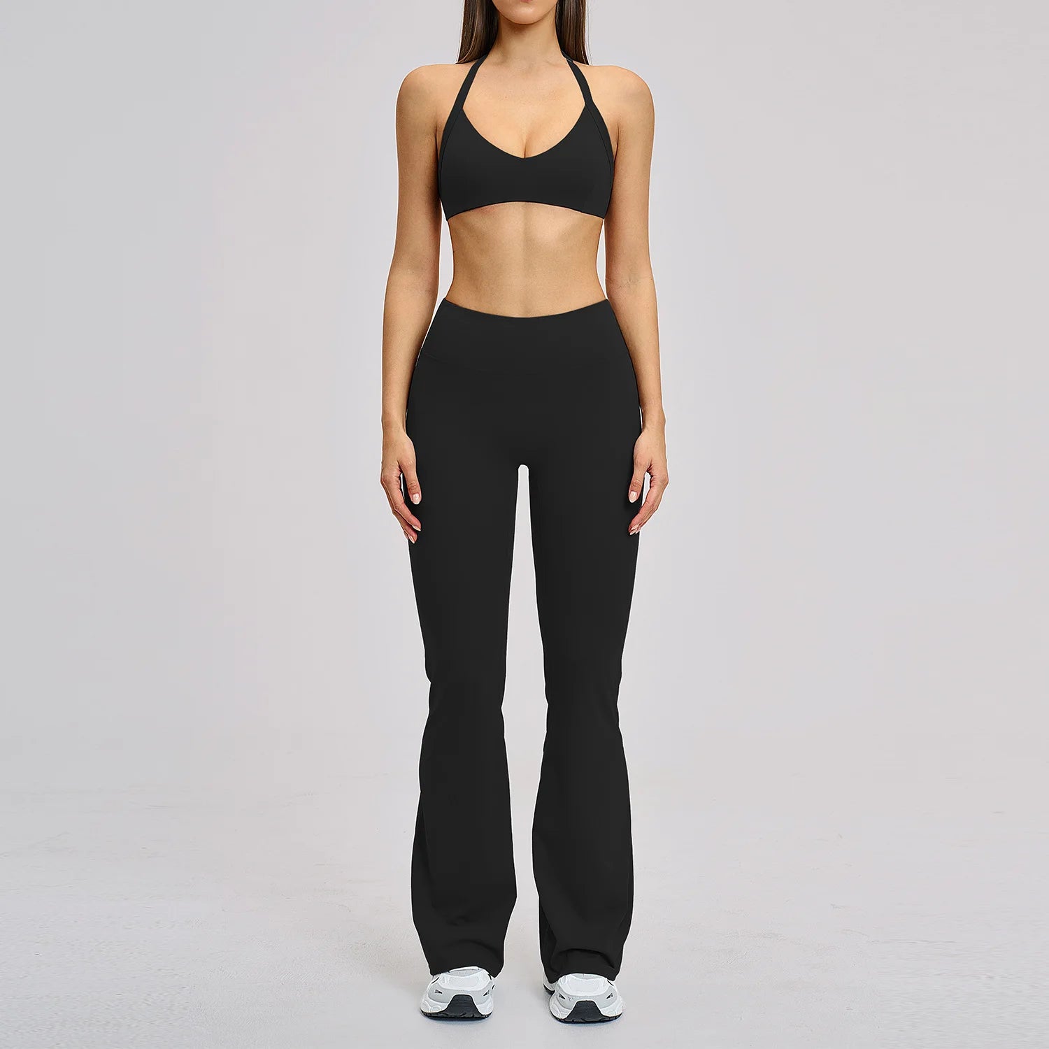 Person wearing a black sports bra and leggings on a gray background