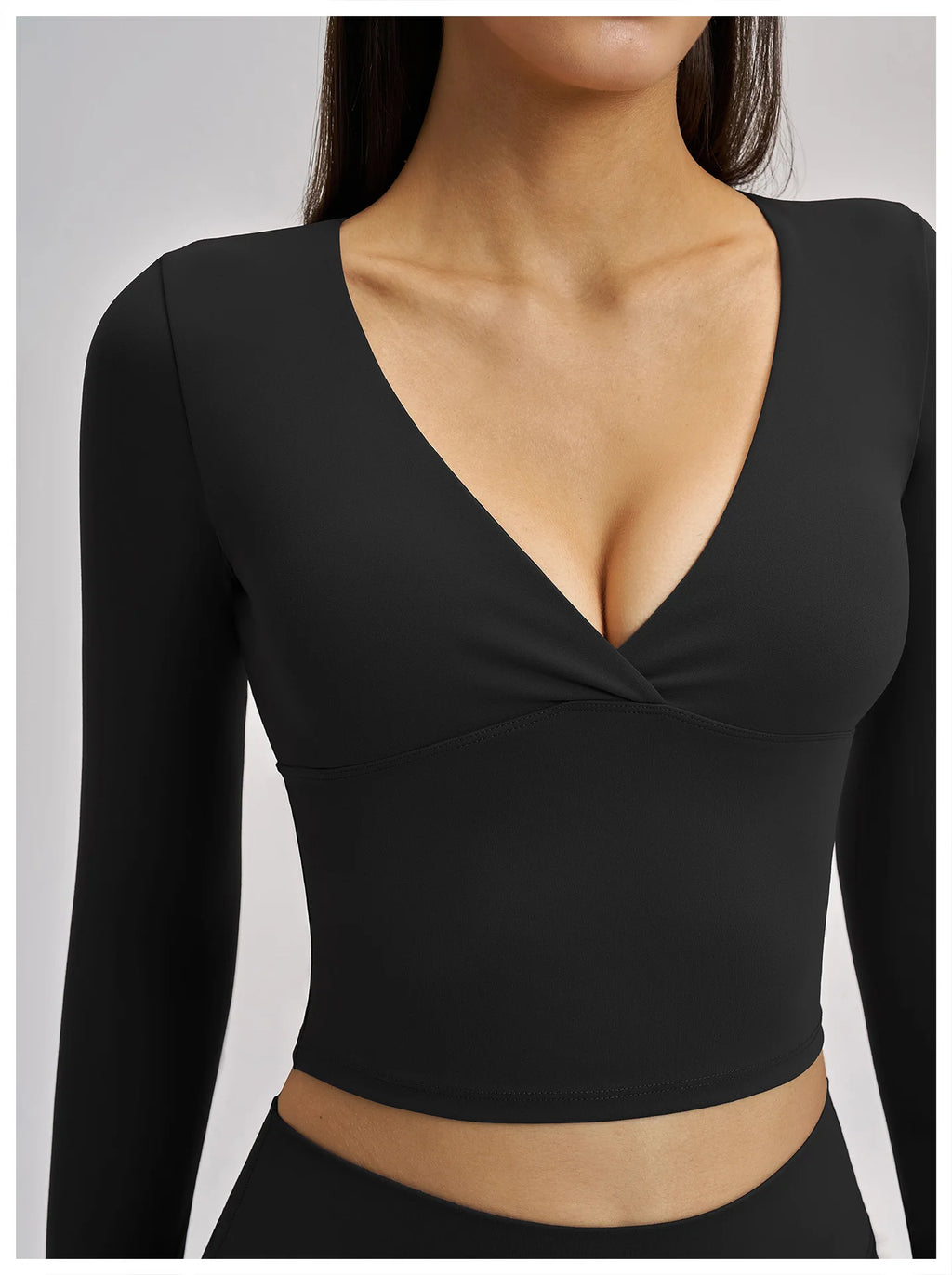 Black long-sleeve crop top worn by a model on a light gray background