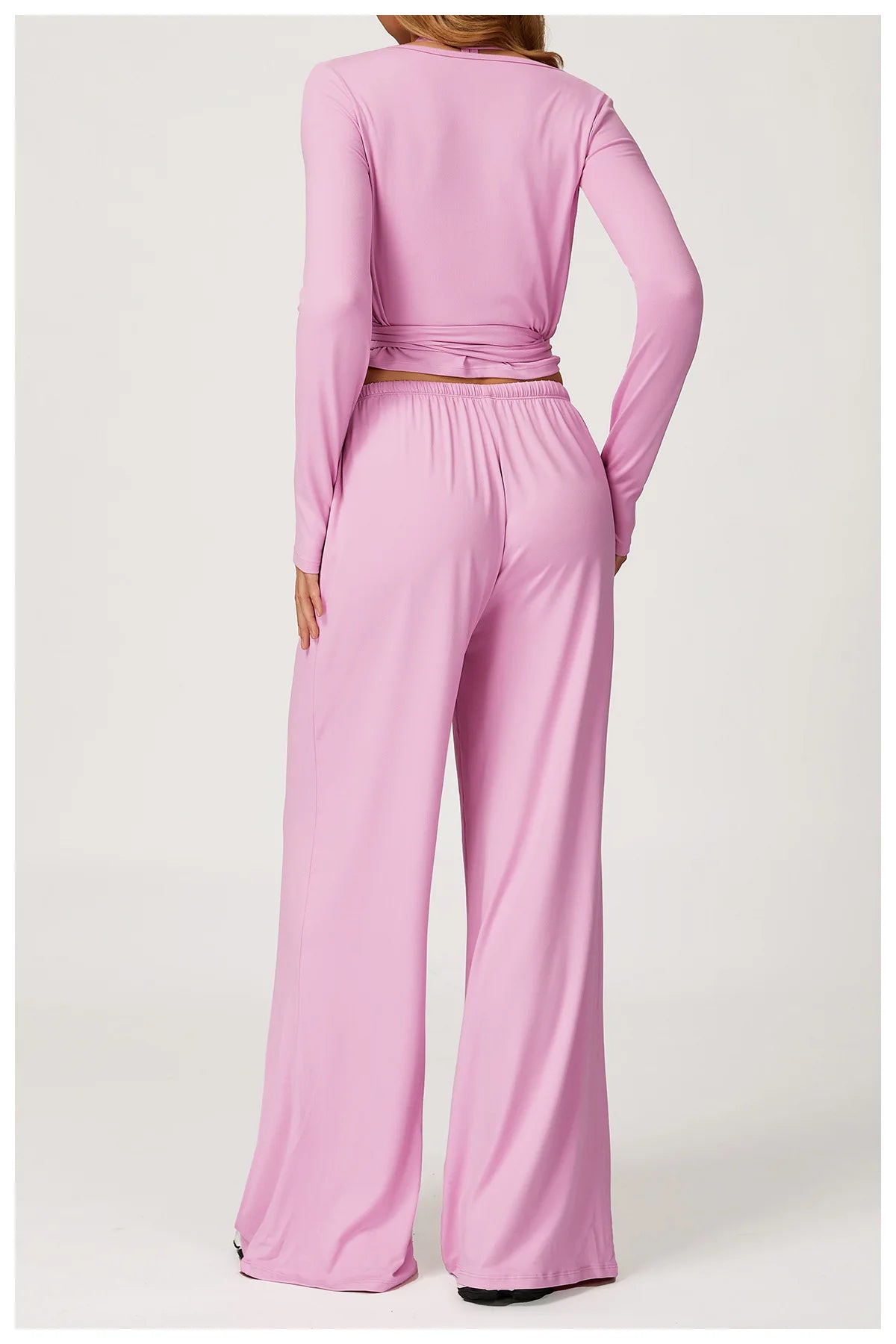 Pink long-sleeve ballet wrap top and wide-leg pants set on a white background