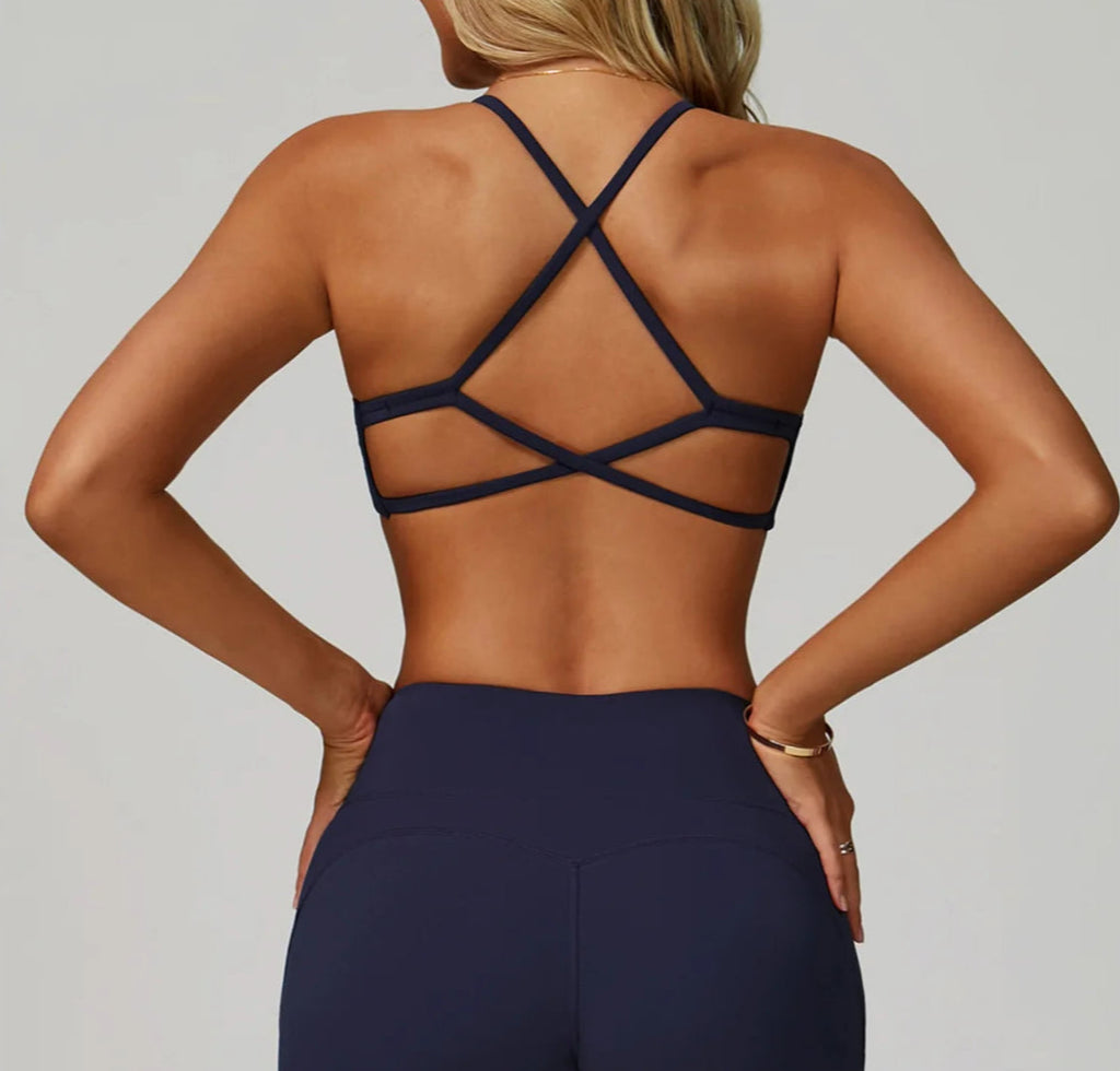 Person wearing a black strappy top and dark blue pants on a light gray background