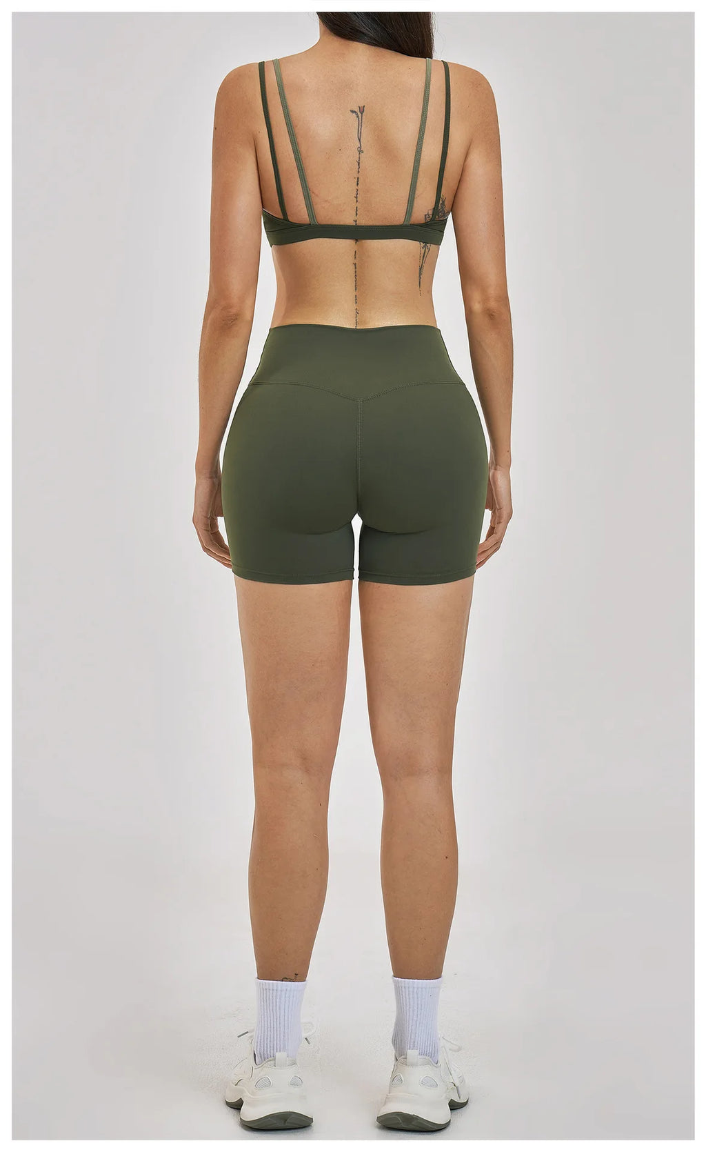 Person wearing green sports bra and shorts on a white background