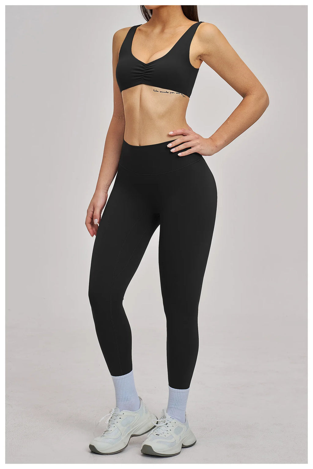 Person wearing black sports bra and leggings on a gray background