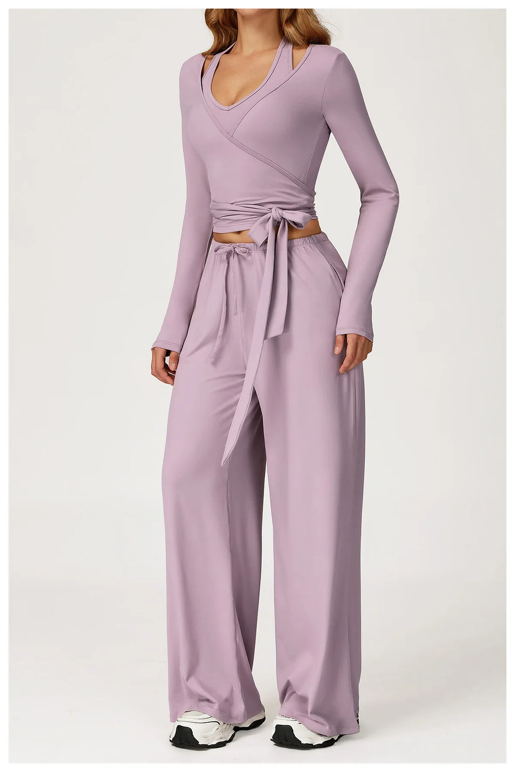 Person wearing a matching purple grey top and pants set on a white background