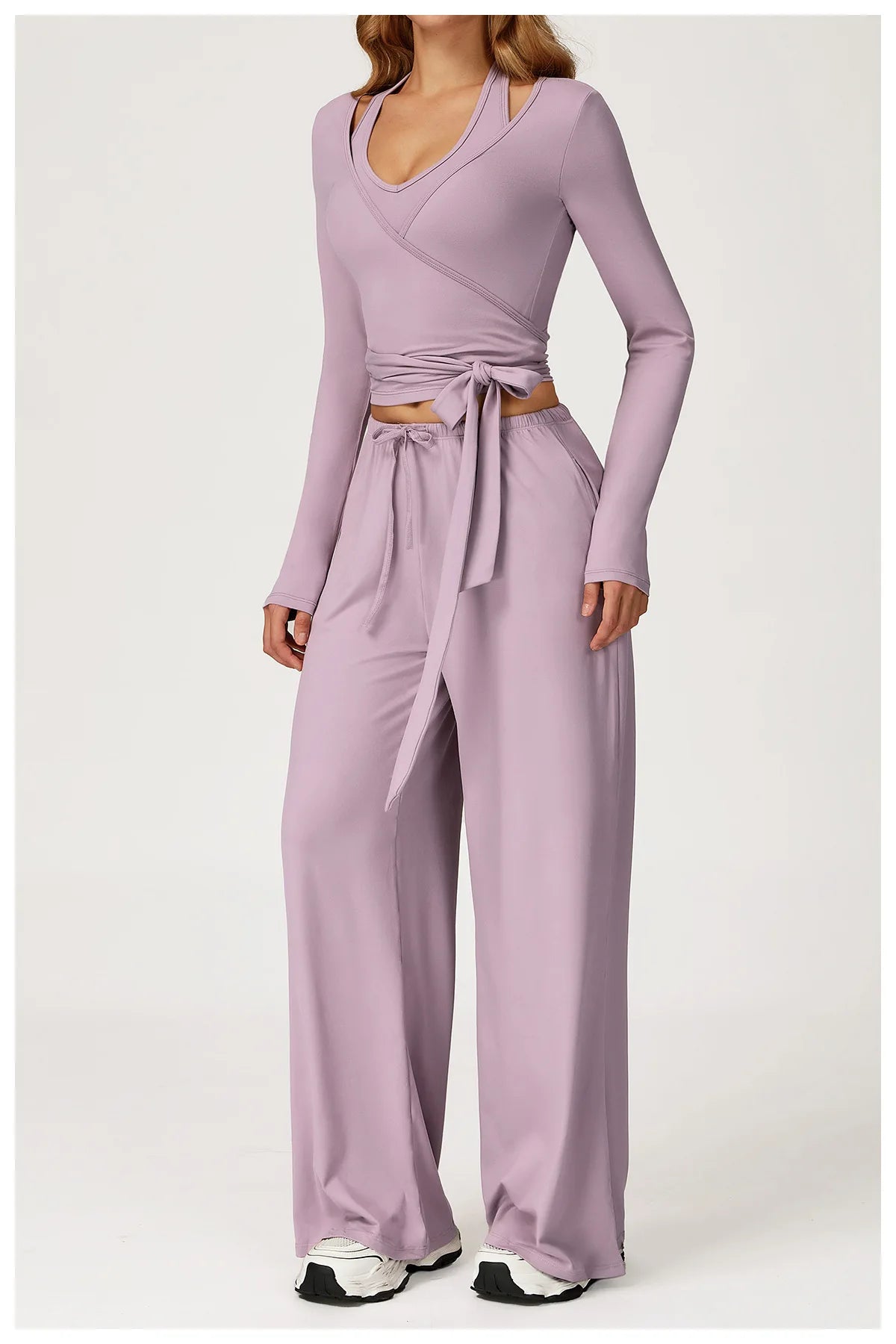 Person wearing a matching purple grey top and pants set on a white background