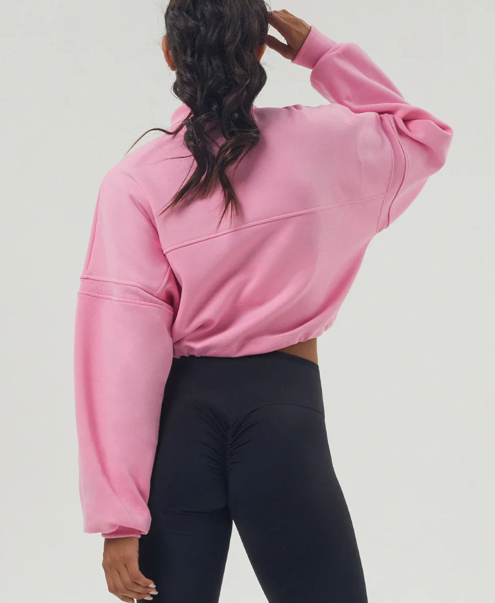 Person wearing a pink cropped hoodie and black leggings on a light gray background