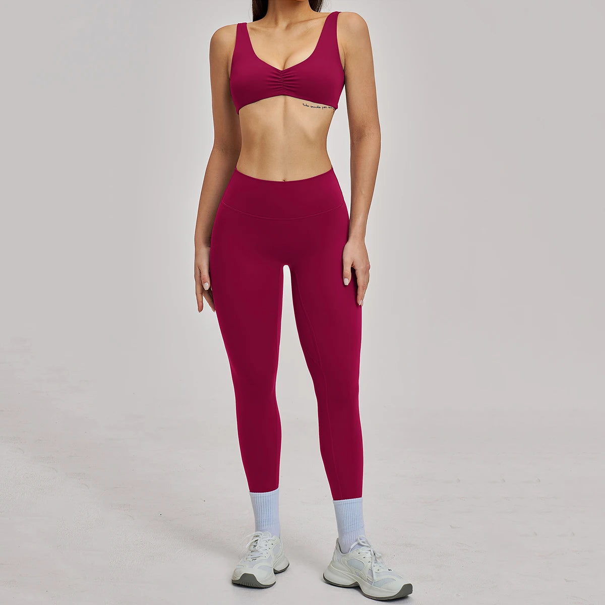Person wearing a maroon sports bra and leggings set on a gray background